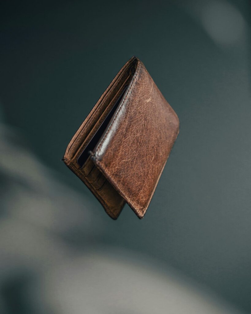 空中で落下している茶色の革の財布。見知らぬ他者への信頼と善意を象徴するイメージ。